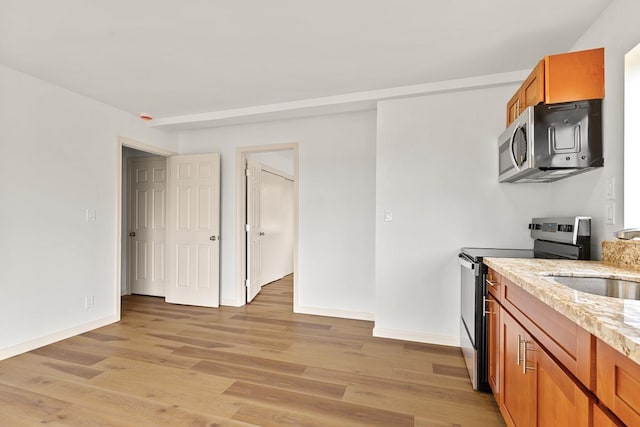 495 Kaiolohia St, Kihei, HI 96753 - kitchen with light stone countertops, brown cabinetry, light wood-style floors, appliances with stainless steel finishes, and a sink