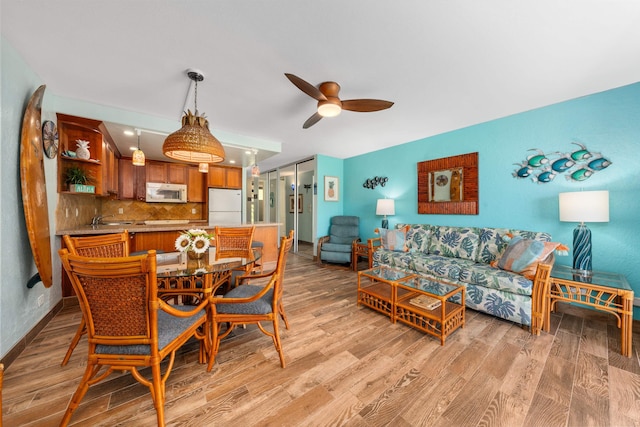 dining room featuring ceiling fan, sink, and light hardwood / wood-style flooring