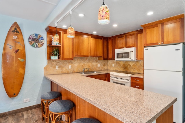 kitchen with kitchen peninsula, white appliances, pendant lighting, and a breakfast bar