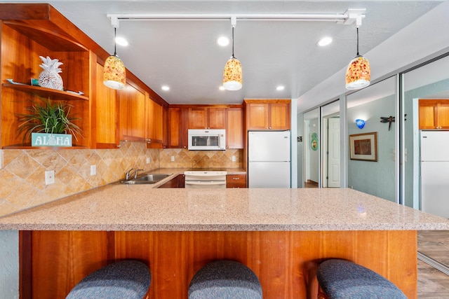 kitchen featuring a kitchen breakfast bar, white appliances, and kitchen peninsula