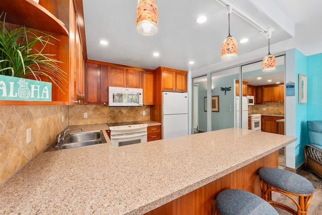 kitchen featuring white appliances, hanging light fixtures, sink, kitchen peninsula, and a breakfast bar