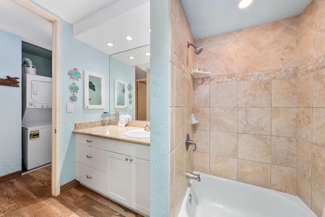 bathroom with vanity, hardwood / wood-style flooring, stacked washer and clothes dryer, and tiled shower / bath