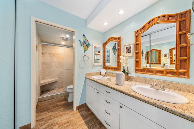 bathroom with wood-type flooring, toilet, a shower with shower door, and vanity