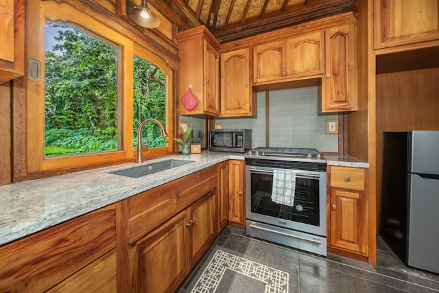 kitchen with light stone countertops, decorative backsplash, appliances with stainless steel finishes, and sink