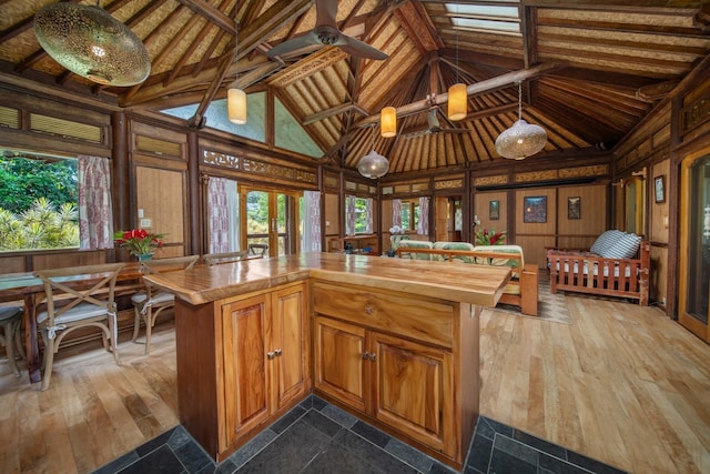 kitchen with wood counters, ceiling fan, wood walls, and high vaulted ceiling