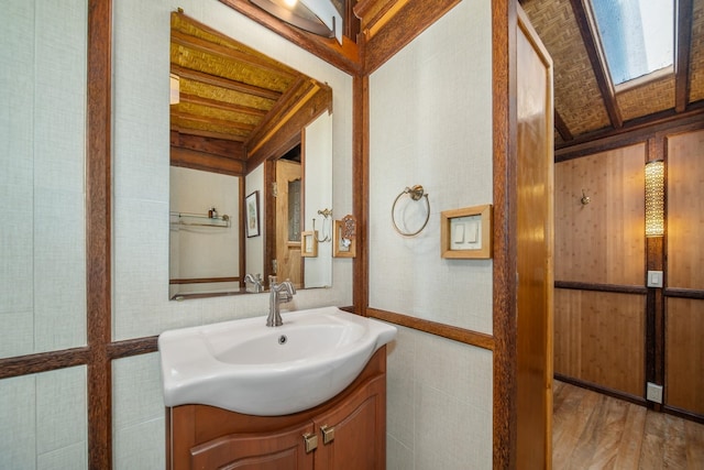 bathroom with vanity, lofted ceiling with skylight, and hardwood / wood-style flooring