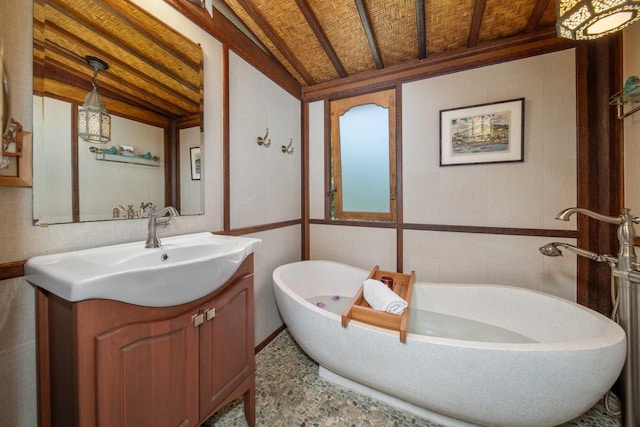 bathroom with vaulted ceiling, a washtub, and vanity