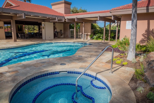 view of swimming pool featuring a hot tub and a patio