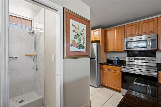 kitchen featuring light tile patterned flooring, stainless steel appliances, and dark stone countertops