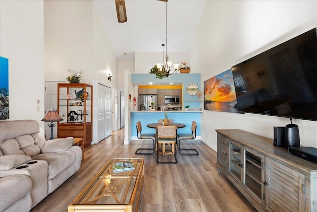 living room with high vaulted ceiling, wood-type flooring, and an inviting chandelier