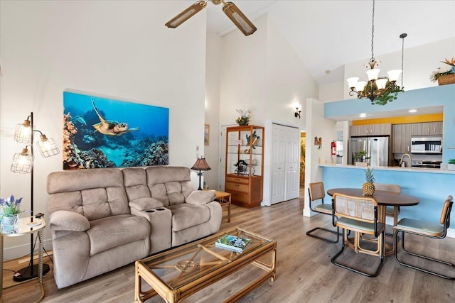 living room with high vaulted ceiling, light hardwood / wood-style flooring, and ceiling fan with notable chandelier