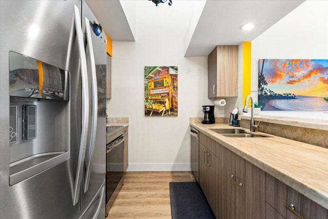 kitchen with dark brown cabinetry, appliances with stainless steel finishes, sink, and light hardwood / wood-style flooring