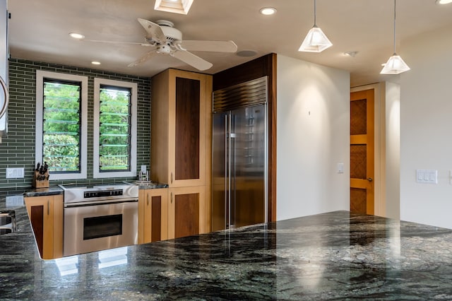 kitchen featuring a skylight, ceiling fan, hanging light fixtures, stainless steel appliances, and decorative backsplash