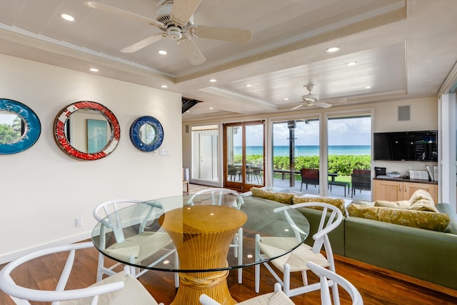 dining room with wood-type flooring, a tray ceiling, and ceiling fan