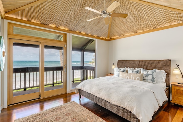 bedroom featuring access to outside, dark hardwood / wood-style flooring, a water view, and a view of the beach