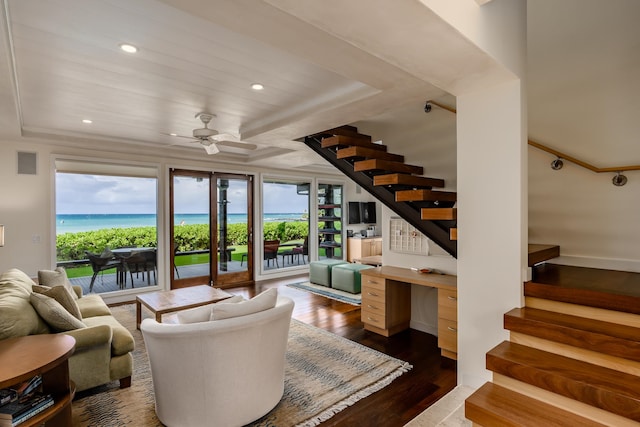 living room with a water view, hardwood / wood-style flooring, and ceiling fan