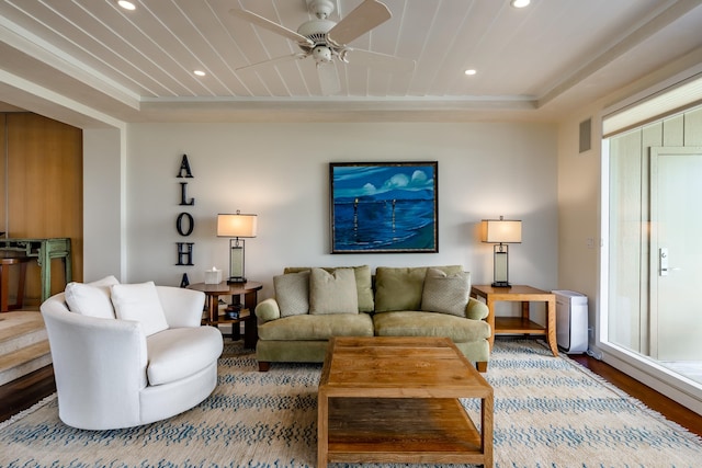 living room with hardwood / wood-style floors, ceiling fan, and a tray ceiling