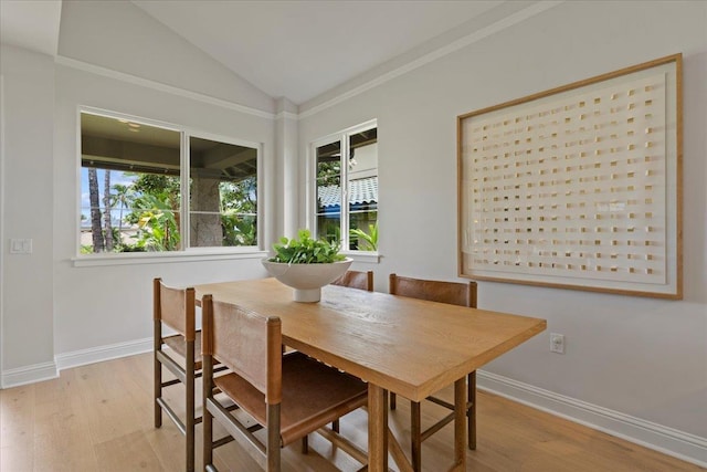 dining area with light wood-type flooring and vaulted ceiling