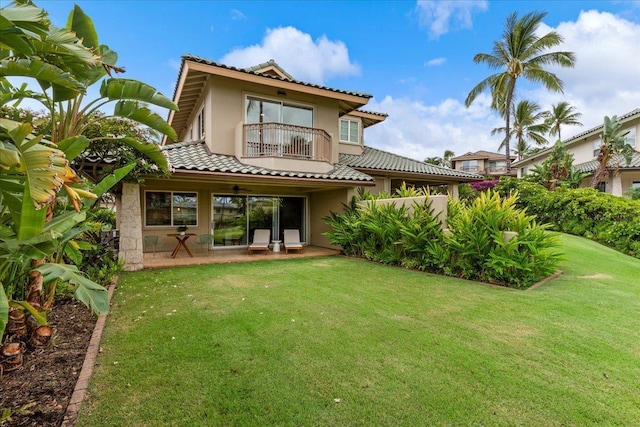 back of property with a balcony and a yard