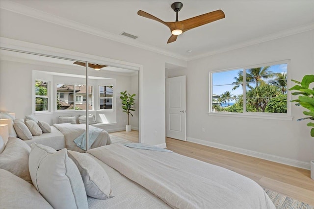 bedroom with multiple windows, light hardwood / wood-style flooring, ceiling fan, and ornamental molding