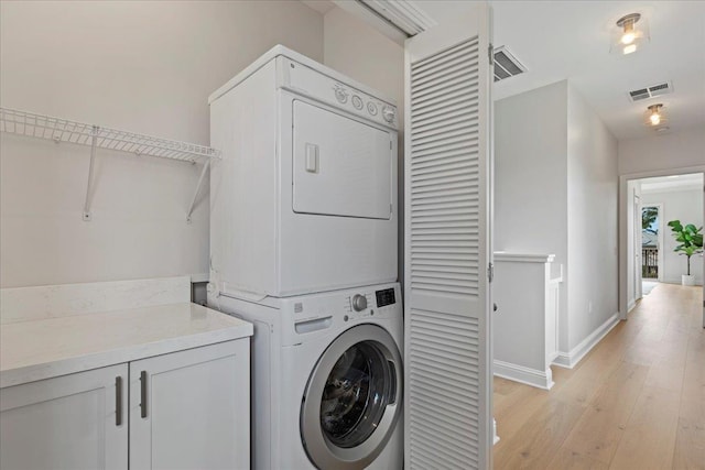 clothes washing area featuring stacked washer and clothes dryer and light wood-type flooring