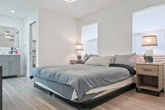 bedroom with ensuite bathroom, recessed lighting, and light wood-style floors