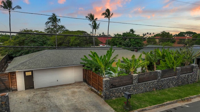 view of front of home featuring driveway, fence, and roof with shingles