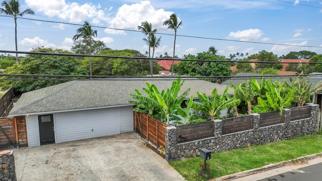 view of front of house with driveway, a shingled roof, and fence