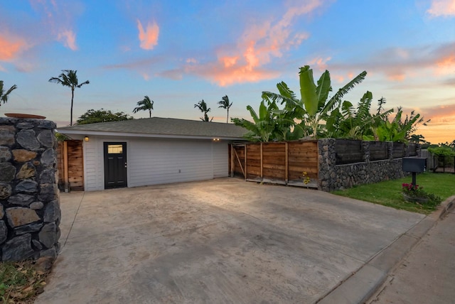 garage at dusk featuring fence