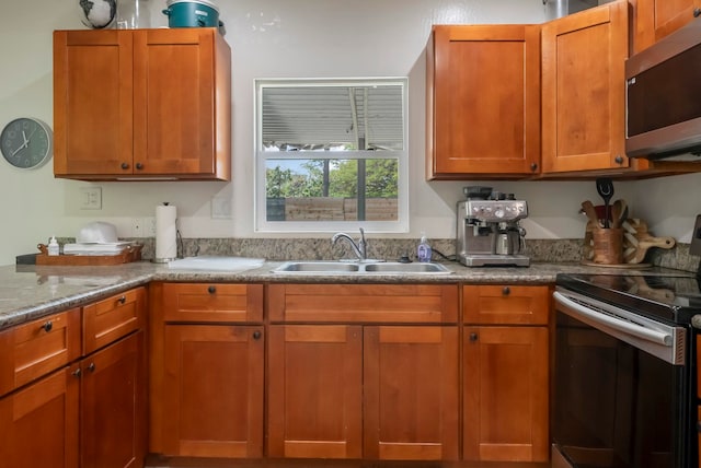 kitchen with a sink, appliances with stainless steel finishes, and brown cabinetry