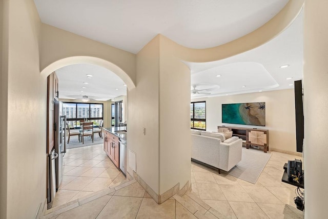 hall with recessed lighting, arched walkways, light tile patterned flooring, and a wealth of natural light