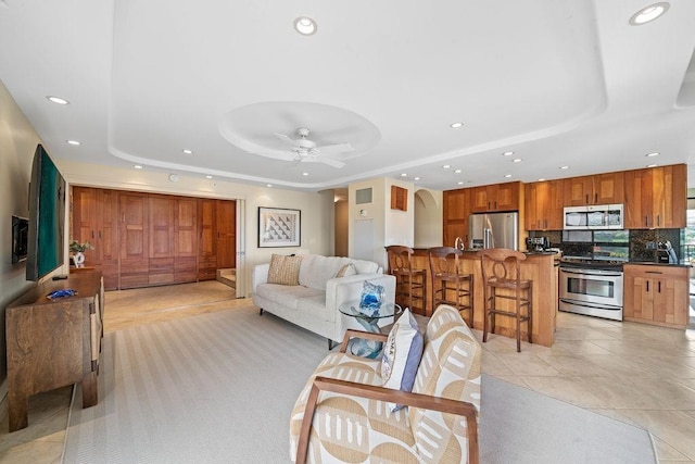 living area featuring recessed lighting, a raised ceiling, ceiling fan, and light tile patterned floors
