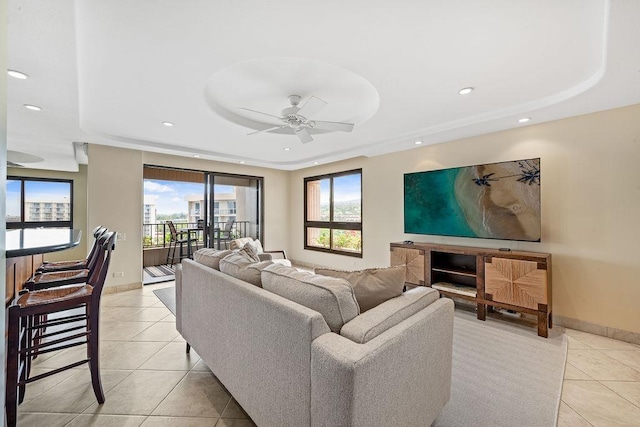 living area featuring a raised ceiling, a ceiling fan, baseboards, recessed lighting, and light tile patterned floors