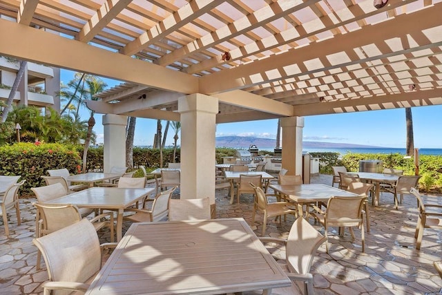 view of patio / terrace featuring a pergola, a water view, and outdoor dining space