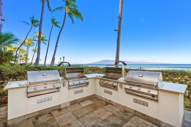 view of patio with grilling area, exterior kitchen, and a water view
