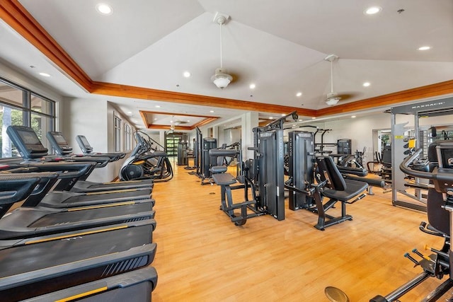 gym with ornamental molding, wood finished floors, lofted ceiling, recessed lighting, and a raised ceiling