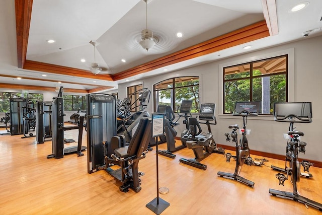 gym featuring baseboards, recessed lighting, a tray ceiling, and wood finished floors