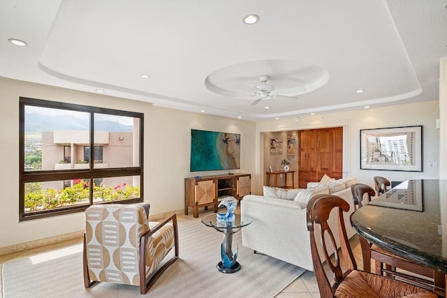living area with light carpet, baseboards, ceiling fan, recessed lighting, and a tray ceiling