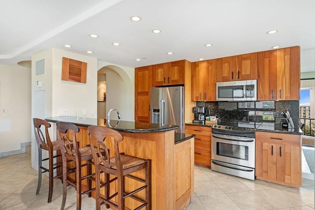 kitchen with decorative backsplash, recessed lighting, brown cabinets, light tile patterned floors, and stainless steel appliances
