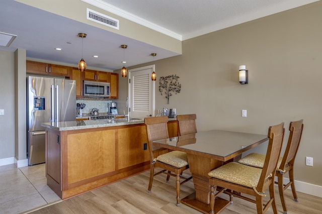 kitchen with light stone countertops, tasteful backsplash, decorative light fixtures, kitchen peninsula, and stainless steel appliances