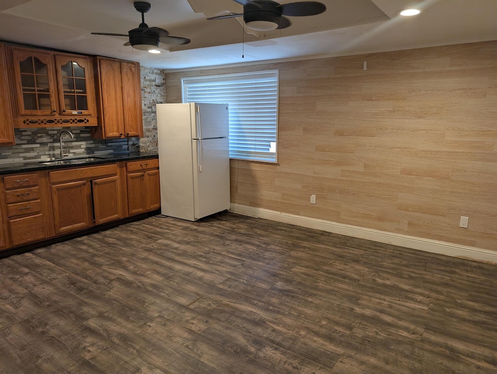 kitchen with dark wood-type flooring, a sink, freestanding refrigerator, brown cabinets, and dark countertops