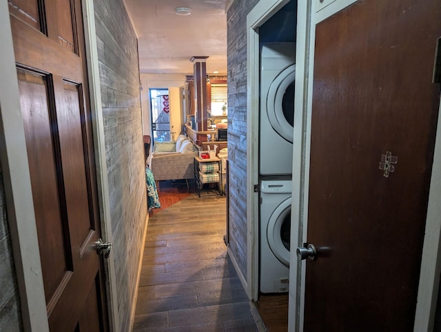 laundry room with laundry area, dark wood finished floors, and stacked washer / dryer