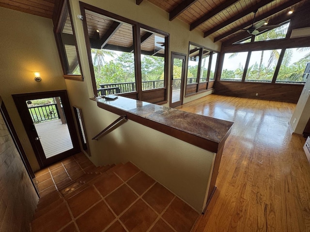 unfurnished sunroom featuring lofted ceiling with beams, wooden ceiling, and ceiling fan