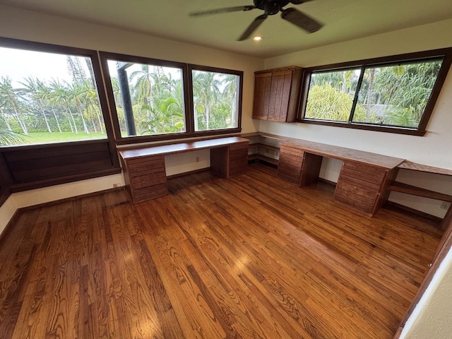 unfurnished office featuring hardwood / wood-style flooring, ceiling fan, and built in desk