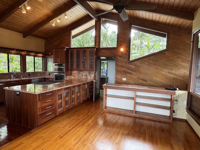 kitchen featuring sink, light stone counters, wood ceiling, a center island, and light wood-type flooring