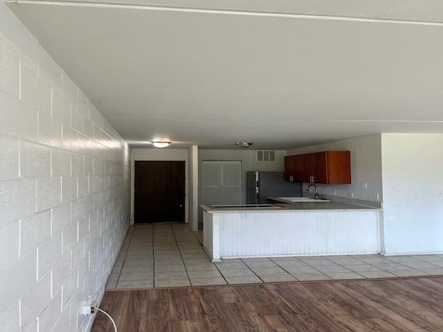 kitchen featuring stainless steel fridge, kitchen peninsula, sink, and light hardwood / wood-style flooring