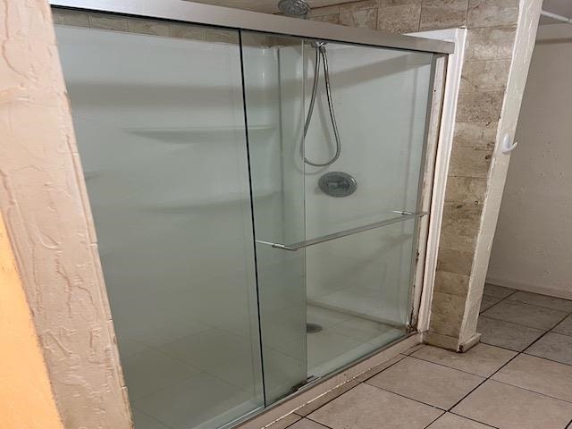 bathroom with tile patterned flooring and a shower with shower door