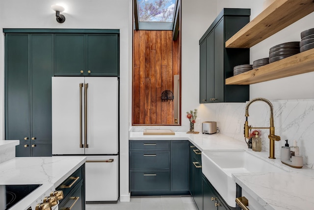kitchen with open shelves, light stone countertops, a sink, and high end white refrigerator