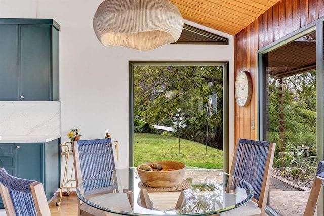 dining space with light wood-style flooring, wooden ceiling, and lofted ceiling