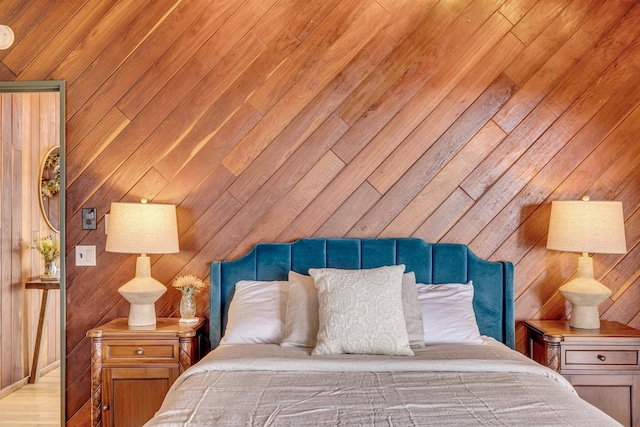 bedroom with light wood-style flooring and wood walls